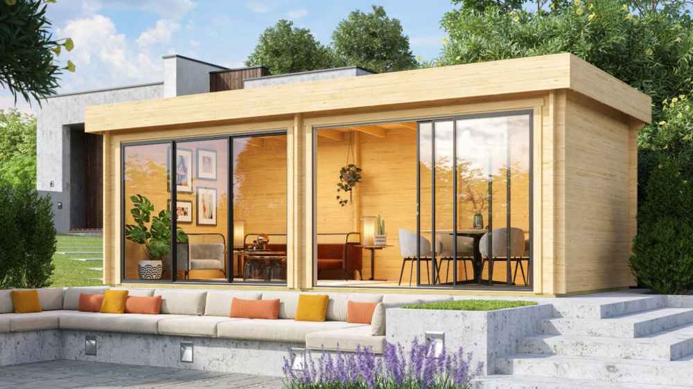 GardenHouse24 USA Lasse 44A ALU Garden Room is set up in a landscaped garden with furniture inside, appearing as a stylish home office or lounge
