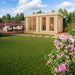GardenHouse24 USA Sauna Giusto 70 Garden Room placed in a landscaped backyard with flowers and decking, blending relaxation and modern style