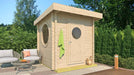 GardenHouse24 USA Sauna Maria 90 Garden Room sits on a sunny patio surrounded by greenery, with a towel hanging outside and round windows visible