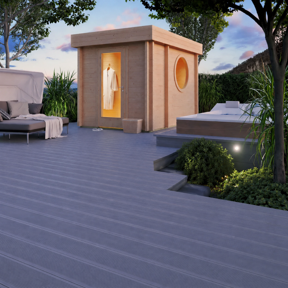 GardenHouse24 USA Sauna Tuuli 90 Garden Room is seen in an elegant backyard setting at dusk, warmly lit from the inside and surrounded by cozy lounge furniture and plants