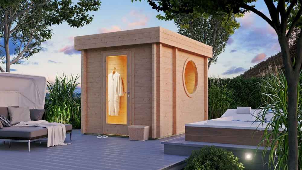 GardenHouse24 USA Sauna Tuuli 90 Garden Room is seen in an elegant backyard setting at dusk, warmly lit from the inside and surrounded by cozy lounge furniture and plants