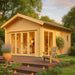 GardenHouse24 USA Sigrid 70 Garden Room with large glass doors and warm lighting on a wooden deck