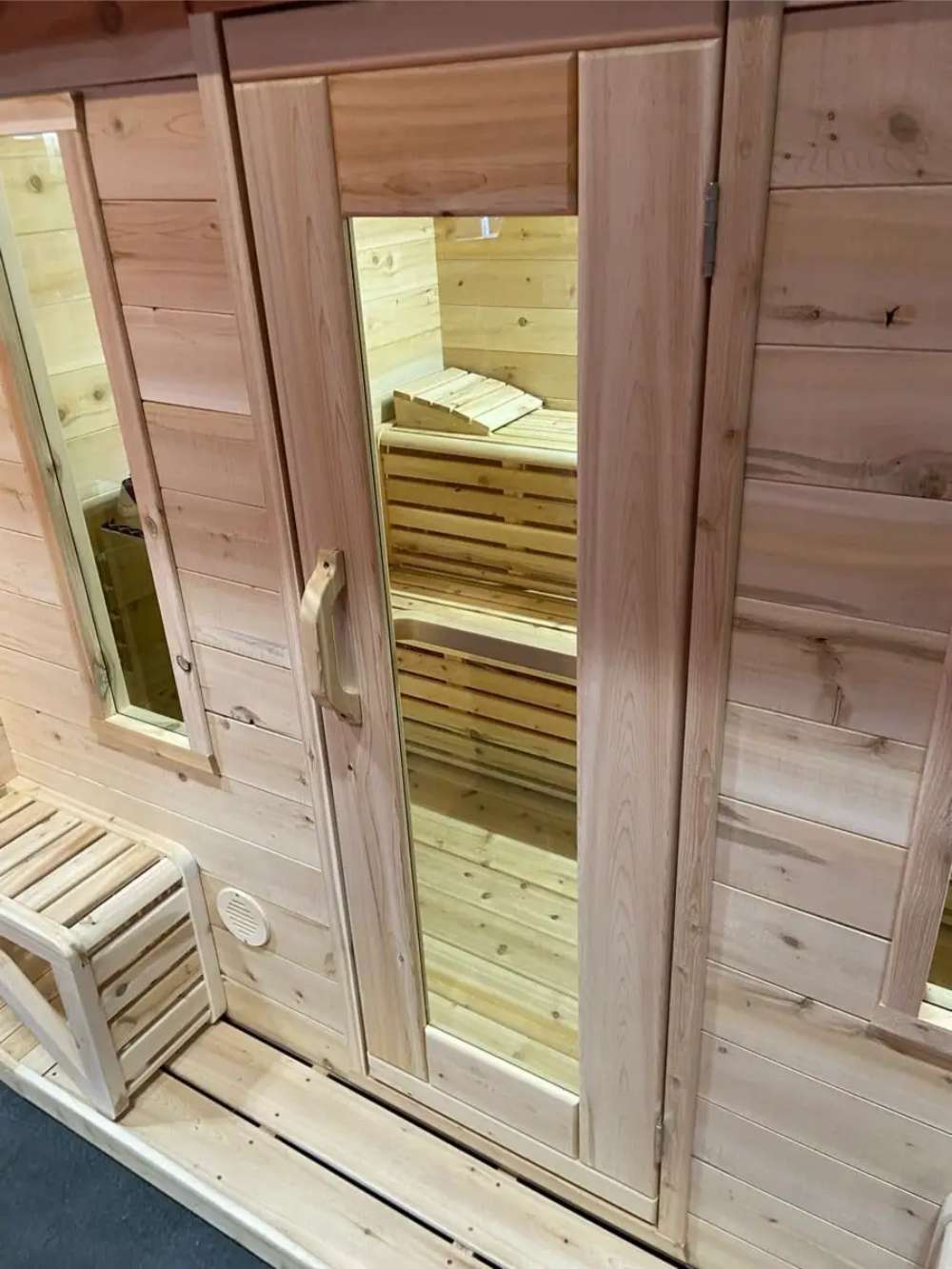Glass-fronted door of Sawmill Structures Box Sauna revealing the wooden bench seating inside