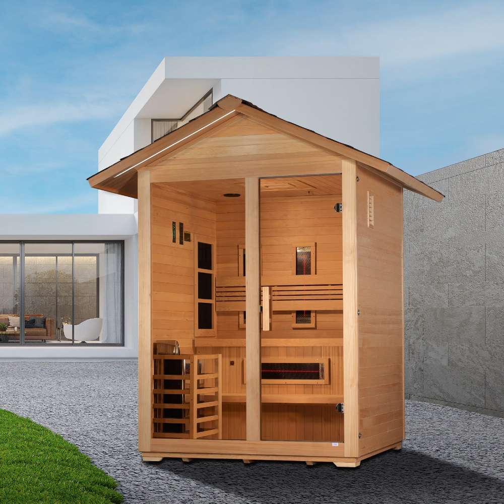 Golden Designs Carinthia 3 Person Hybrid Outdoor Sauna on a gravel patio beside a lawn in front of a modern white building