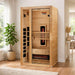 Golden Designs Dynamic Gracia 1-2 Person Full Spectrum Near Zero EMF Far Infrared Sauna stands in a bright living room beside a window and a potted plant