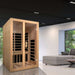 Golden Designs Dynamic Santiago 2 Person Low EMF Far Infrared Sauna stands in a modern living room with a gray sofa and a large window