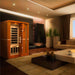 Golden Designs Dynamic Vittoria 2 Person Low EMF Far Infrared Sauna stands in a warmly lit living room with a sofa and dark floor