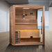 Golden Designs Hanko 2-3 Person Traditional Sauna stands on a gray wood floor in a bright room with a window looking out over the sea
