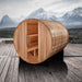 Golden Designs Klosters 6 Person Barrel Traditional Sauna sits on a wooden deck in front of snowy mountains under a cloudy sky