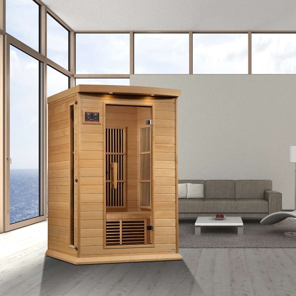 Golden Designs Maxxus 2 Person Near Zero EMF Far Infrared Sauna in Hemlock stands in a bright room with tall windows and a gray sofa