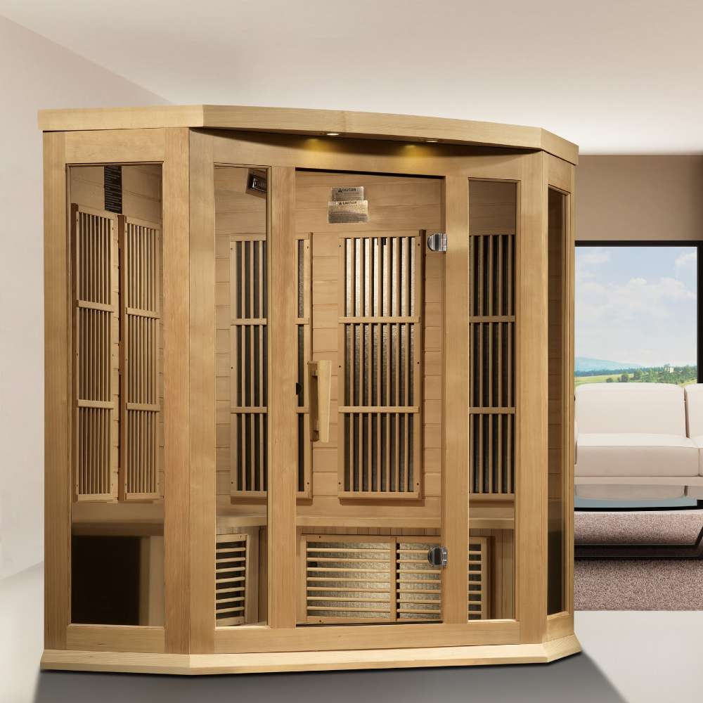 Golden Designs Maxxus 3 Person Near Zero EMF Far Infrared Corner Sauna in Hemlock stands in a bright room beside a large window