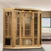 Golden Designs Maxxus 3 Person Near Zero EMF Far Infrared Corner Sauna in Hemlock stands in a bright room beside a large window