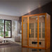 Golden Designs Maxxus Alpine Dual Tech 3 Person Low EMF Far Infrared Sauna stands in a bright living room with tall windows and a white sofa