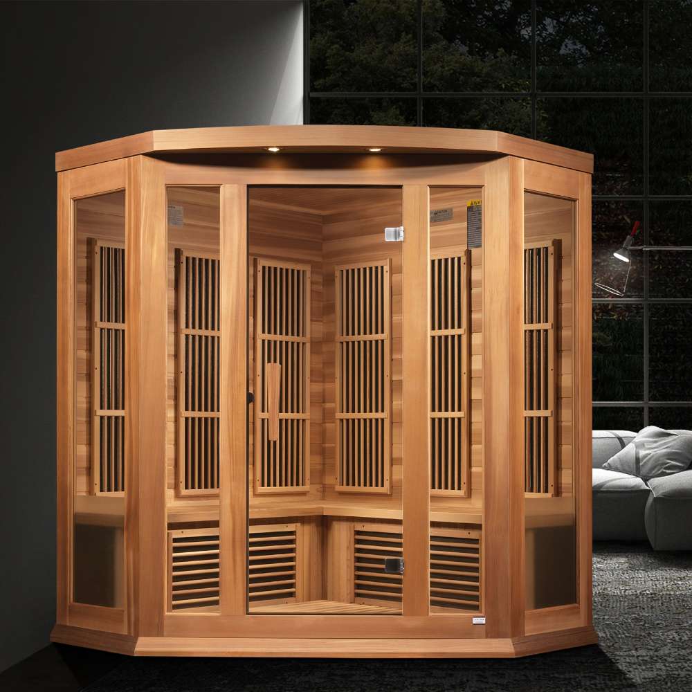 Golden Designs Maxxus Avignon 3 Person Corner Near Zero EMF Far Infrared Sauna in Red Cedar glows with accent lights in a dark modern room beside a gray sofa