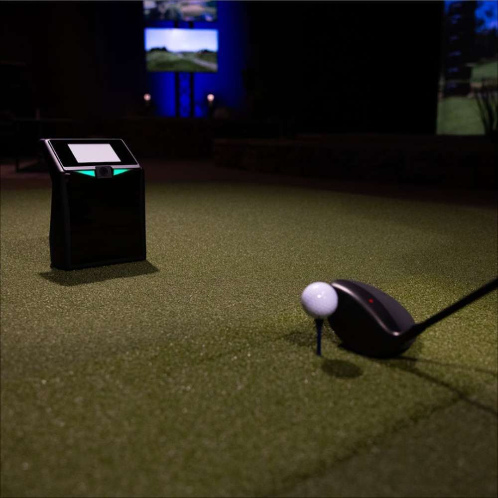 Golf ball on a tee is positioned next to the launch monitor in an indoor setup from TruGolf LaunchBox Golf Launch Monitor w/ Starter 10 (2025) Enclosure + Gimme Package