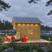 Side view of the GrandView 150 cabin with smooth wooden siding, a gray metal roof, red outdoor chairs and modern pathway lighting.