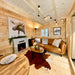 Grand Loft 107 Deluxe DD living room with warm wood walls, a brown leather sofa, cowhide rug, fireplace and large moose artwork.