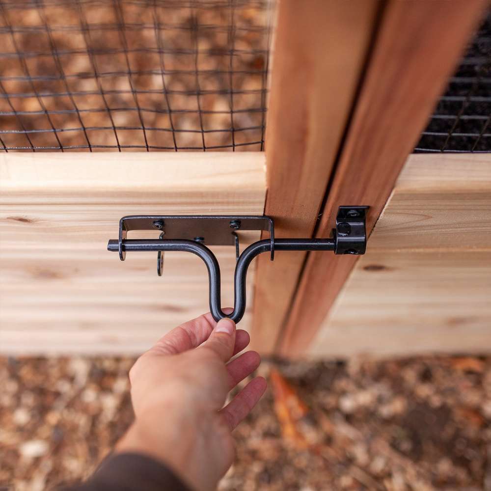 Hand secures the metal latch on the gate of Outdoor Living Today 8×5 Raised Garden Bed, showing how it closes tightly
