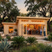 A wooden Harbord 70 backyard cabin transformed into a bar at golden hour. Guests mingle inside and outside the folding glass doors.