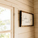 Framed “Lake Life Is the Best Life” wall sign beside a sunlit wooden window inside the Harvest Grand Bungalow.