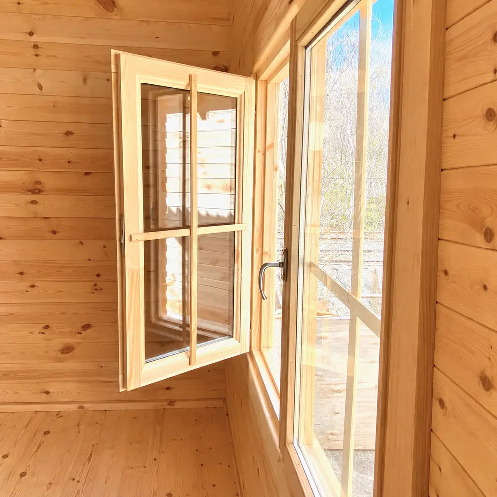 Open wooden-framed casement window admitting bright sunlight into the pine-paneled Harvest Grand Bungalow interior.
