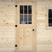 Solid pale-wood exterior door with a six-pane window grid, black hinges and a round black handle on the Harvest Grand Bungalow.