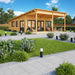 GardenHouse24 USA Hedland 70 Garden Room is shown in a sunny garden setting with outdoor furniture and glass doors inviting natural light into the space