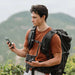 Hiker charges a smartphone outdoors using Jackery Explorer 100 Plus Portable Power Station with Mini Carrying Bag