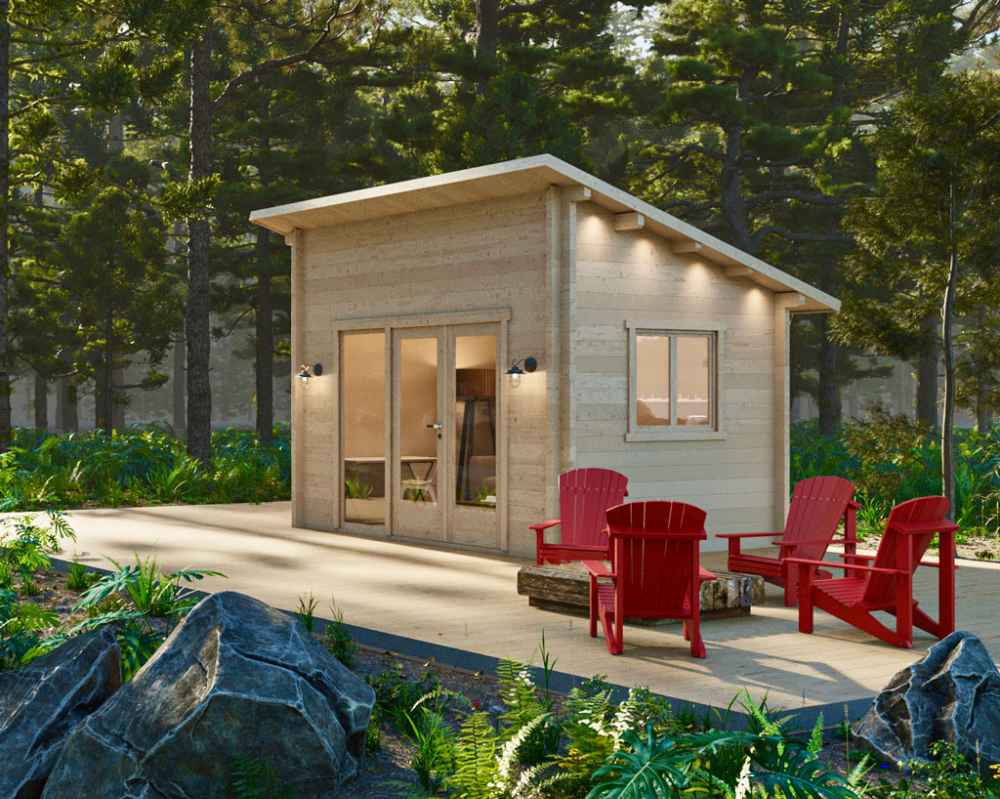 In a forest clearing, the Sawmill Structures The Versa 107 70MM Garden Room glows warmly beside a seating area with rustic logs and red chairs