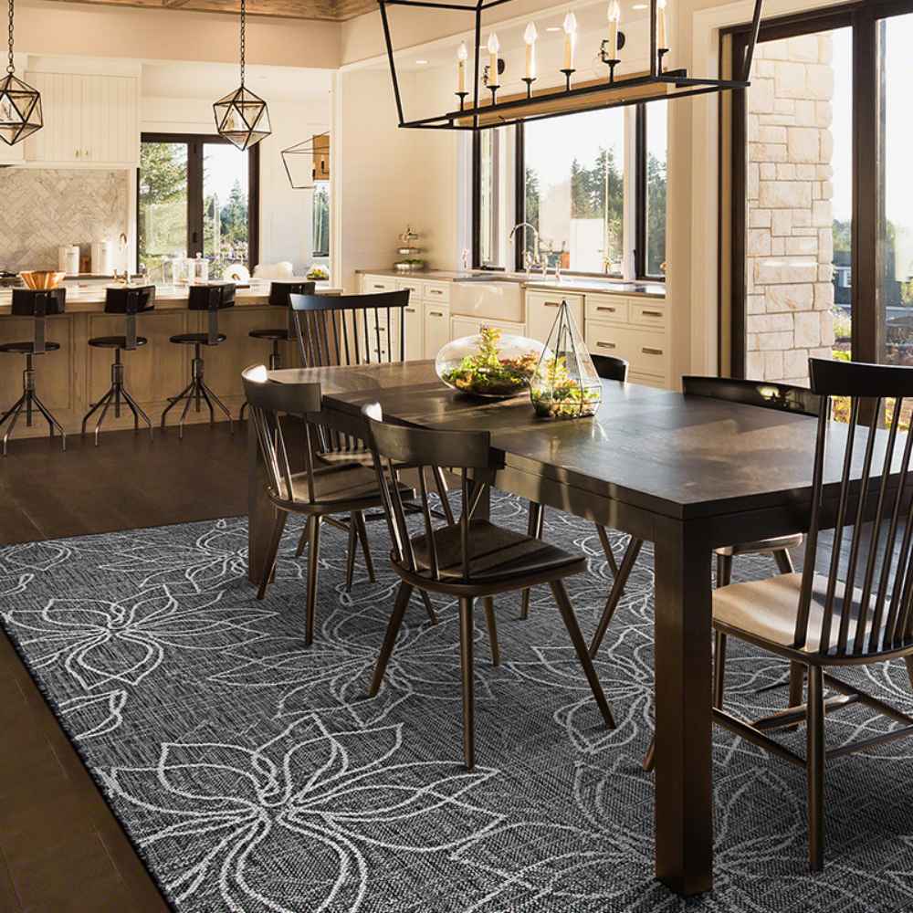 In a cozy kitchen-dining space, the Couristan Charm Indoor/Outdoor Rug - Botanical/Ash lies under the table, adding contrast with its bold floral design