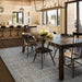 In a modern dining room, the Couristan Charm Indoor/Outdoor Rug - Ohe/Sand-Ivory lies under a dark wood table, adding subtle elegance with its muted grid design