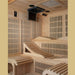 Inside Golden Designs Monaco Near Zero EMF Far IR Sauna, a fold-down screen and speakers hang from the ceiling above reclining wood benches and heater grilles