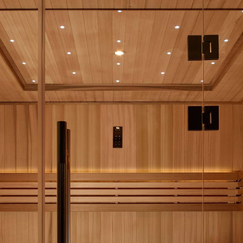 Inside Golden Designs Osla 6 Person Traditional Sauna, tiny star lights dot the cedar ceiling above a black door handle and softly lit backrest boards