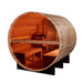 Inside Golden Designs Zurich 4 Person Barrel with Bronze Privacy View Traditional Sauna, cedar benches and a guarded stove sit beside the glass door looking out at palm trees