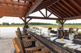 Inside the Brookside Timber Frame Combolan Estate Pavilion, a well-designed outdoor bar and dining area create a luxurious space