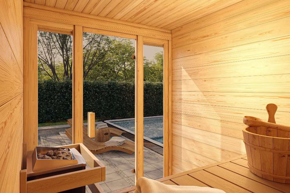 Inside Sawmill Structures TS TwoSauna Sauna, warm wooden benches and soft lighting create a peaceful view looking out toward a sunny poolside