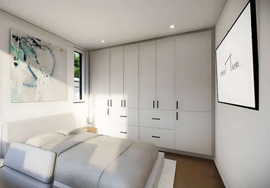 Inside Sawmill Structures The Tremblant Garden Suites a cozy white bedroom features a large bed, full-wall cabinetry, abstract art, and a wall-mounted TV