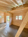 Inside Sawmill Structures The Versa 240 70MM Garden Room, wooden beams stretch overhead above a bright open area with multiple windows