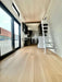 Inside Sawmill Structures Wanderlove Tiny Home, there’s a bright open hallway with wood flooring, white shiplap walls, and a stairway leading to a loft