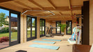 Inside the GardenHouse24 USA Game Room 70 Garden Room, a spacious workout area is equipped with treadmills, yoga mats, gym gear, and large windows offering a scenic garden view