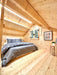 Inside the Sawmill Structures Ontario Grand Loft 107 SD Garden Room, a cozy loft bedroom features natural wood walls, slanted ceiling, and a double bed