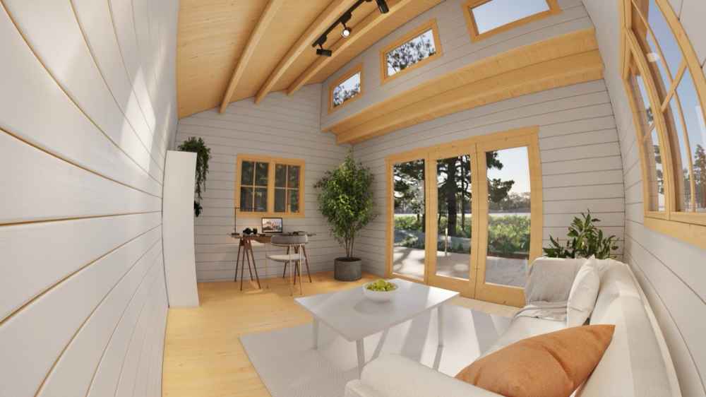 Inside the Sawmill Structures The Versa 160 Atrium 70MM Garden Room, a cozy, sunlit living space features a white couch, desk, and tall windows framed by wooden beams