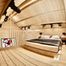Inside the loft of the Sawmill Structures Grand Loft 107 Deluxe DD Garden Room, a clean and modern bedroom features a low platform bed and black track lighting on the wood ceiling