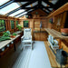 Inside the Outdoor Living Today 8×12 Sunshed Garden Shed, a white rocking chair, wooden shelves, and fresh vegetables create a cozy, functional workspace