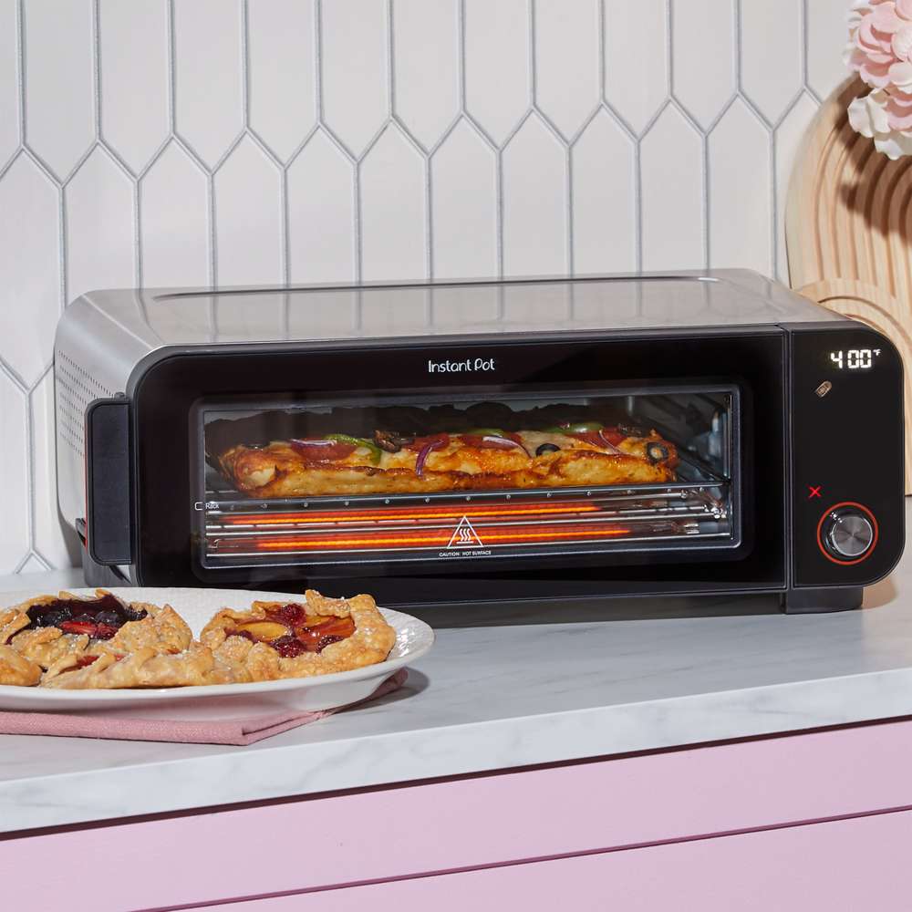 Instant Pot® InstantHeat™ Pizza Oven cooks a pizza at 400°F with baked pastries displayed on the counter in front