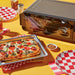 Instant Pot® InstantHeat™ Pizza Oven sits on a yellow table beside a rectangular pizza, checkered plates, and seasonings