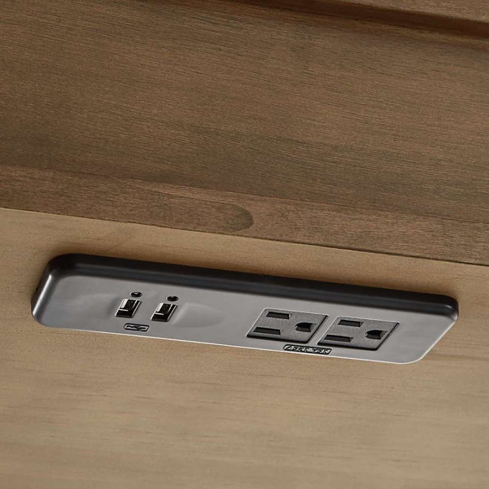 Integrated USB ports and power outlets under Crate & Barrel Tate Walnut Bookcase Desk with Outlet for easy device charging