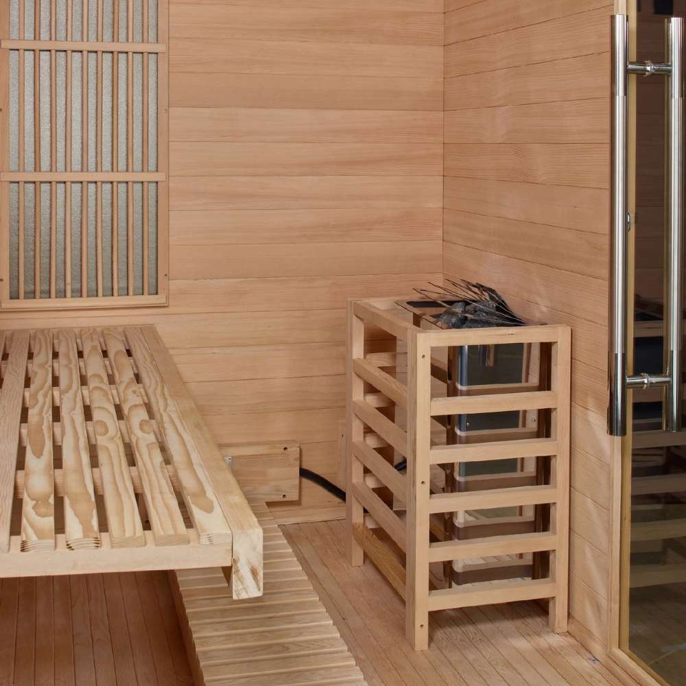Interior corner of Golden Designs Soria 3 Person Indoor Hybrid Sauna with Full Spectrum IR and Harvia Stove showing a slatted cedar bench and the Harvia stove in a wood safety guard