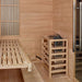 Interior corner of Golden Designs Soria 3 Person Indoor Hybrid Sauna with Full Spectrum IR and Harvia Stove showing a slatted cedar bench and the Harvia stove in a wood safety guard