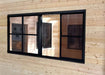 Interior of Sawmill Structures Eze Breeze Sunroom Cabin shows a black-framed sliding window on a smooth pine wall